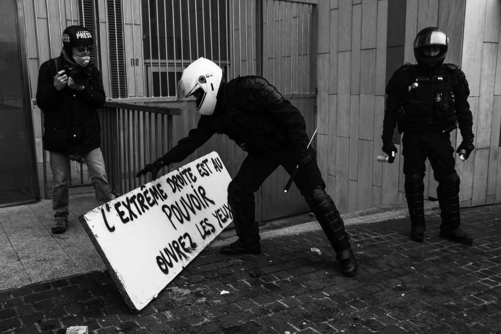 A policeman removes a sign. A few thousand people took to the streets to celebrate the first anniversary of the yellow vest movement, Paris on 16 November 2019. Un policier enlève une pancarte. Quelques milliers de personnes sont sorties dans les rues pour fêter les 1 an du mouvement des gilets jaunes,  Paris le 16 novembre 2019.